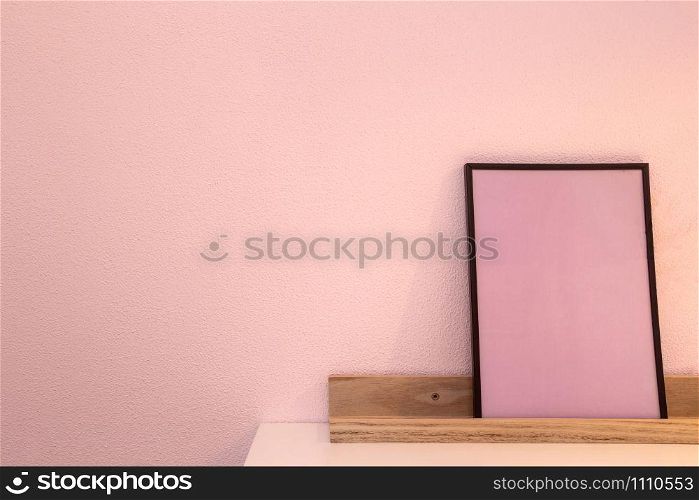 Pink blank mock up of photo frame on the light background. Home interior, wooden shelf near pink wall close-up. Pink blank mock up of photo frame on the light background. Home interior, wooden shelf near pink wall