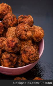 Pink bowl with fried meatballs with spices. Homemade food.