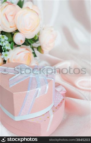 Pink camellias and two gift boxes with bow on a background of the silk fabric