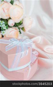 Pink camellias and two gift boxes with bow on a background of the silk fabric