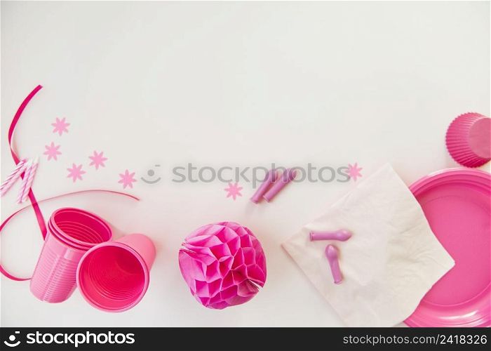 pink candles plastic glasses tissue paper plates honeycomb paper ball white background