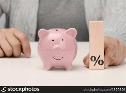 pink ceramic piggy bank and wooden blocks with with percent sign. Concept of increasing interest on a deposit in a bank, high return on investment, large margin on sale