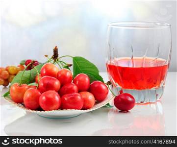 pink cherries on a plate and a glass of juice