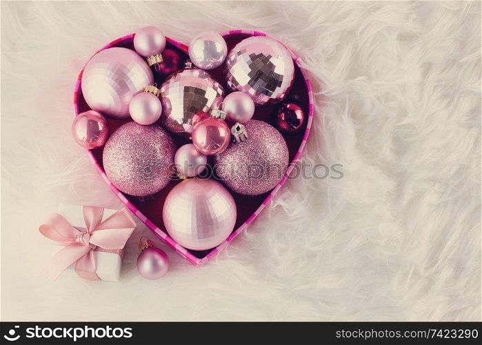 Pink Christmas decorations in box on white fur, retro toned. Pink Christmas decorations on white fur