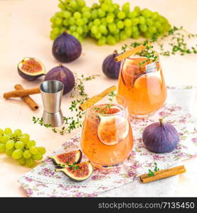 Pink cocktail with fig, thyme, cinnamon and grapes in glass on pink concrete background, close up. Autumn drinks and alcoholic cocktails. Alcoholic cocktail or detox drink