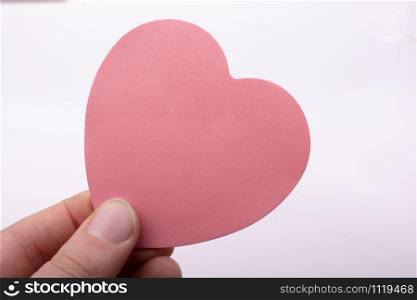 Pink color heart shaped paper in hand as love concept
