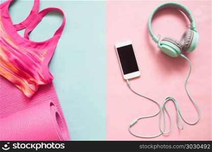 Pink color sport bra and yoga mat with smartphone and earphones . Pink color sport bra and yoga mat with smartphone and earphones on pastel color background, Healthy lifestyle concept