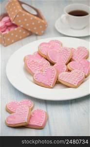 pink cookies in the shape of hearts on a plate and a cup of tea and gift boxes on Valentine&rsquo;s Day. cookies in the shape of hearts on Valentine&rsquo;s Day