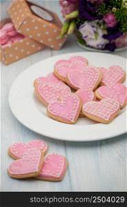 pink cookies in the shape of hearts on a plate and gift box and flowers on Valentine&rsquo;s Day. cookies in the shape of hearts on Valentine&rsquo;s Day