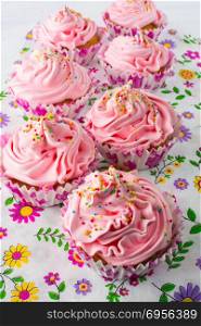 Pink cupcakes on floral pattern napkin. Pink cupcakes on floral pattern napkin. Homemade cupcake. Sweet dessert. Sweet pastry. Gourmet cupcakes. Sweet cupcake. Birthday cupcakes.