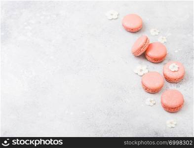 Pink dessert cake macaron or macaroon with white sweet flowers on stone kitchen background.