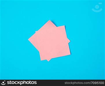 pink empty paper square stickers on blue background, copy space