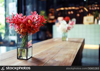 Pink flower in vase stands on table in a cafe for background