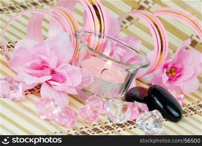 pink flowers, burning candle and colored pieces of ice