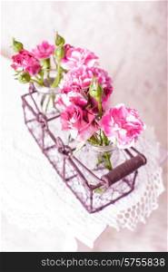 Pink flowers in glass bottles in metal basket. Vintage decor concept. Pink flowers