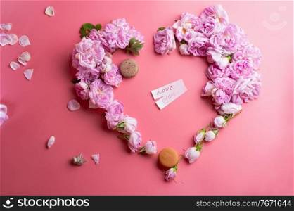  pink fresh fragrance roses  in heart shape with macaroon  around pink  background. romantic and beauty concept  