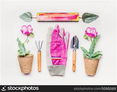 Pink Gardening equipment flat lay for planting, weeding, pruning with garden tools, flowers seedling plant in pot and Gloves on white table background, top view