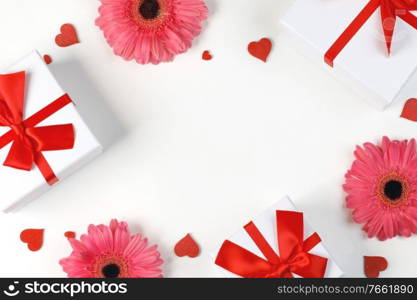 Pink gerbera flowers gifts and red hearts composition on white background top view with copy space. Valentine’s day, birthday, wedding, Mother’s day concept. Copy space. Flowers gifts and hearts background