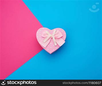 pink gift box in the form of a heart with a bow on a blue background, top view, festive backdrop