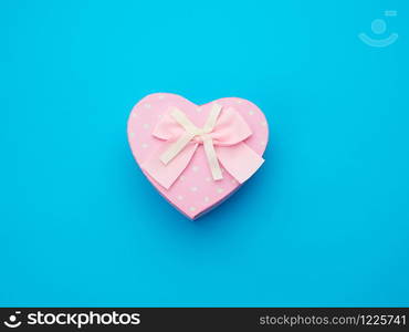 pink gift box in the form of a heart with a bow on a blue background, top view, festive backdrop