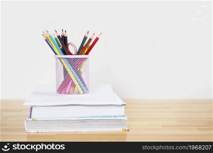 pink glass with colored pencils on a stack of books. copy space.