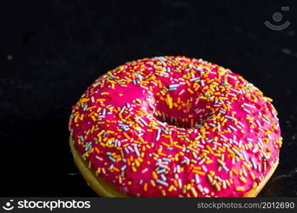 Pink glazed donut with sprinkles isolated. Close up of colorful donut.