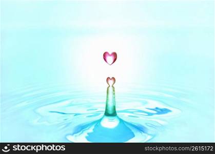 Pink heart shaped water droplets falling into blue water