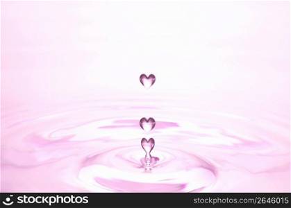 Pink heart shaped water droplets falling into pink water