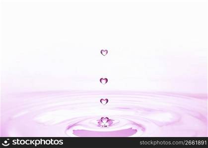Pink heart shaped water droplets falling into pink water