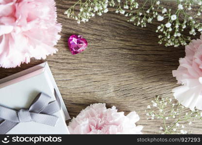 Pink heart with gift box and carnation flowers on wooden background