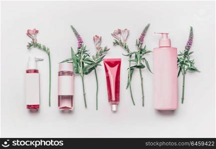 Pink herbal natural facial cosmetic products set with herbs and flowers on white background, top view. Branding mock up