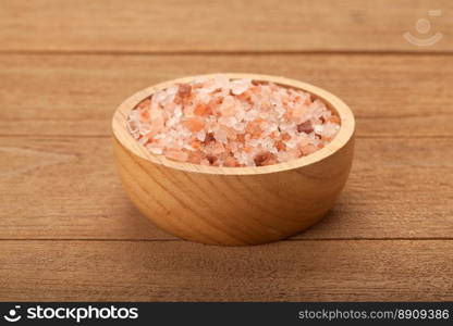 Pink Himalayan salt in wooden bowl on wood background