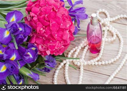 pink hortensia and violet irise  flowers and bottle of fragrance
