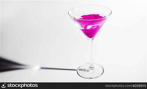 pink ink dissolving martini glass isolated white backdrop