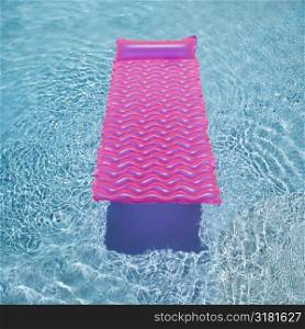 Pink lounge float in empty swimming pool.