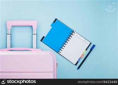 Pink luggage with a checklist diary on blue background for travel planning concept