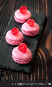 Pink macarons - sweet meringue-based confection decorated with fresh raspberries