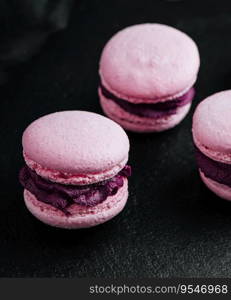 Pink macarons with chocolate filling on black stone