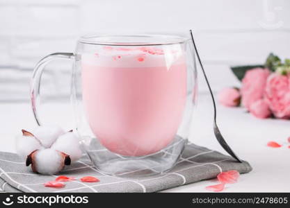 Pink matcha with rose petals on a white background. Transparent cup with trendy vegan whipped tea. Moon milk. Relaxing drink for sleepy time.. Pink matcha with rose petals on white background. Transparent cup with trendy vegan whipped tea. Moon milk. Relaxing drink for sleepy time.