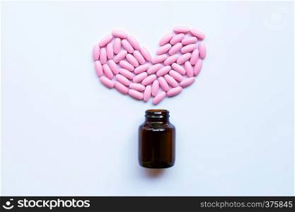 Pink medicine pills on white background. Heart shape