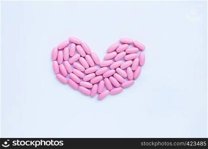 Pink medicine pills on white background. Heart shape