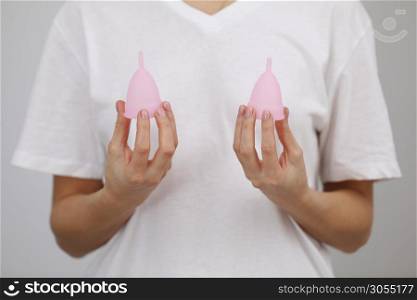 Pink menstrual cups. Close up of woman hand holding different size menstrual cups. Women health concept, zero waste alternatives