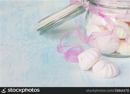 Pink meringue in a glass jar with ribbon close-up