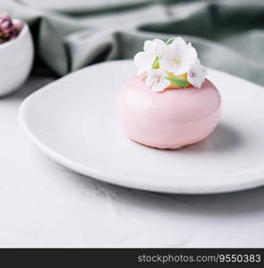 Pink mousse cake decorated with white flowers
