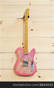 Pink paisley Fender guitar on wood grain wall