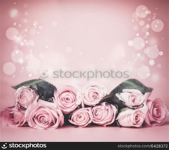 Pink pale floral background with roses bunch on table with bokeh. Holidays greeting layout or wedding concept