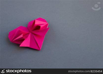 Pink paper heart origami isolated on a blank grey background. Valentines day card. pink paper heart origami isolated on a grey background