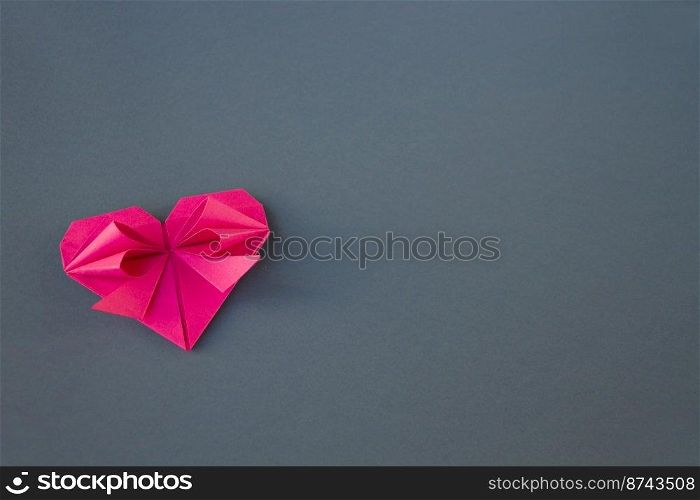 Pink paper heart origami isolated on a blank grey background. Valentines day card. pink paper heart origami isolated on a grey background