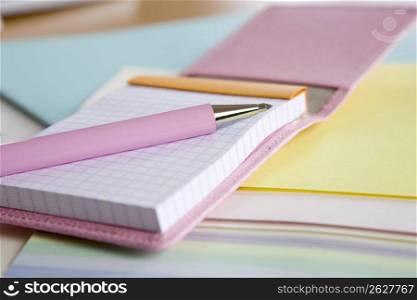 Pink pen laying on notebooks