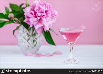 Pink peony next to glass of pink wine. pink background. Pink peony next to glass of pink wine.